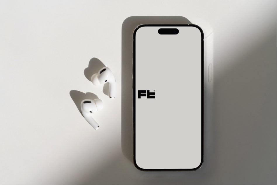 Flat lay of phone with wireless earbuds casting shadows on white surface